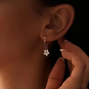 Nahaufnahme eines filigranen Ohrrings mit Blumenanhänger und funkelnden Schmucksteinen.