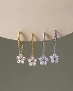 Detaillierte Nahaufnahme exquisiter Gold- und Silber-Blumen-Zirkonia-Hängecreolen.