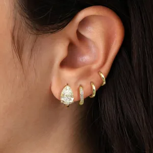 Detailed close-up view of layered gold hoop earrings featuring sparkling pear-shaped zirconia.