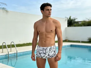 Close-up detail shot of men's black and white bamboo print elastic swim trunks by pool.