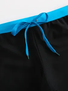 Close-up detail of men's swim trunks waist with blue drawstring and contrast waistband.