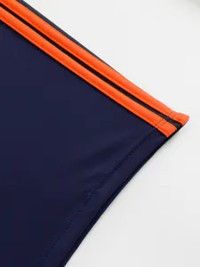 Close-up detail of men's swim trunks featuring contrast side stripes and neat stitching.
