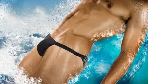 Close-up detail shot of men's sexy minimal black thong swim brief in splashing water.