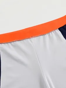 Close-up view of men's swim trunks featuring an orange waistband and white mesh fabric.