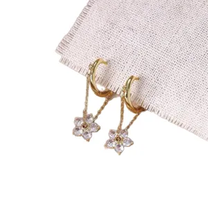 Elegante goldene Blumen Ohrringe mit funkelnden Zirkonia Kristallen und feinen Ketten für Damen.