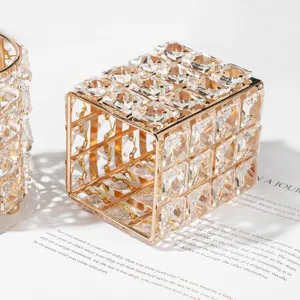 Detailed close-up of crystal makeup brush holder, gold metal frame with glass cubes.