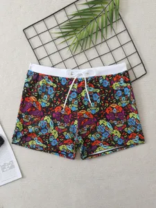 Detail view of men swim trunks with colorful skull floral print and white drawstring waistband.