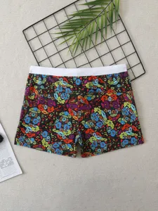 Detailed view of men's board shorts with colorful floral skull print and white waistband.