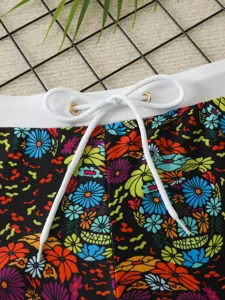 Close-up of men swim trunks featuring colorful skull floral print and white adjustable drawstring.