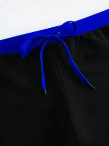 Men's swim trunks detail shot showing blue drawstring elastic waistband and smooth black fabric.