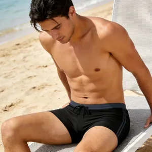 Detail view of men solid black swim trunks featuring drawstring and stylish side stripe design.
