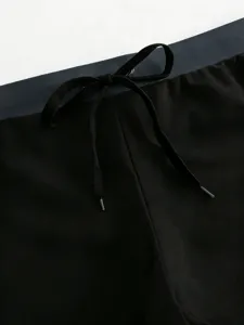 Detailed close-up of black men's swim trunks waistband featuring adjustable drawstring.