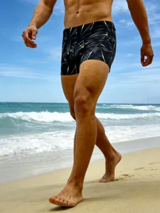 Close-up detail of men's geometric printed swim trunks showcasing beachwear style and fit.