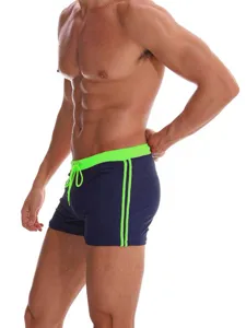 Detail view of men's nylon swim trunks with neon green waistband, drawstrings and side stripes.
