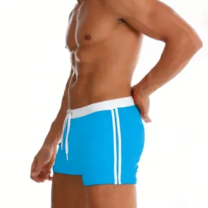 Detail view of men's blue swim trunks featuring white waistband, drawstring, and side stripes.