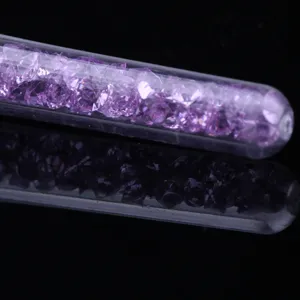 Gros plan de strass violets dans le tube de poignée transparent pour pinceau à ongles.
