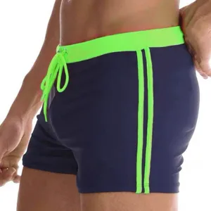Men's slim fit solid color flat angle swim trunks with neon green waistband and side stripes.