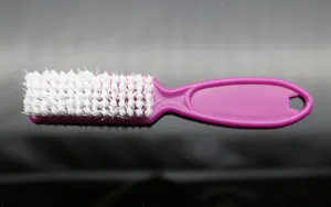 Nail art cleaning brush with purple plastic handle and white stiff bristles for dust removal.
