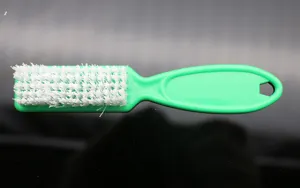 Nail cleaning brush tool for manicure dust removal, hard bristle plastic brush detail view.