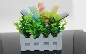 Detail shot of colorful plastic nail cleaning brushes arranged neatly inside a white decorative fence pot.