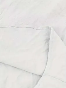Primer plano detallado de tela de lino y algodón gris claro con textura y costuras.