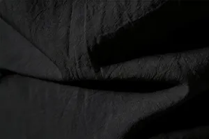 Close-up view of premium black crinkled fabric texture showing soft touch and fine detail.