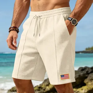 Detail view of men's waffle knit casual beach shorts with drawstring and flag patch.