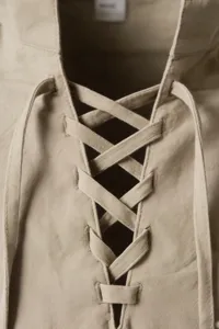 Close-up detail of men's vintage casual lace-up collar shirt in solid beige linen fabric.