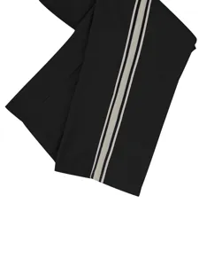 Primer plano detallado de pantalones casuales negros con rayas laterales en contraste.