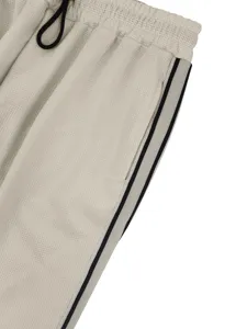 Detalle de pantalón informal de punto gofrado con cordón elástico y bandas laterales.