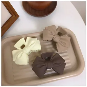 Matte bow hair claw clip detail shot, elegant brown and cream claw clips for styling high ponytails.