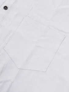 Vista detallada del bolsillo en el pecho y botón de la camisa de lino con fina textura.