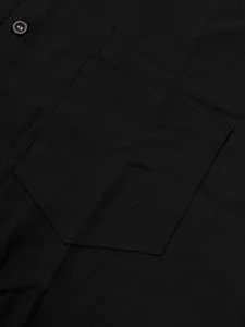 Primer plano de la textura de la tela, bolsillo en el pecho y botón de la camisa negra.