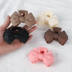 Matte bow hair claw clip detail, stylish pastel shark clip for elegant updos and half hairstyles.
