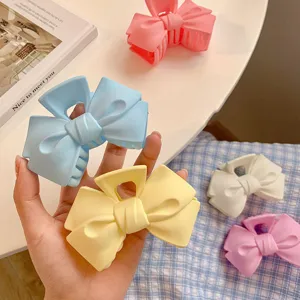 Matte bow hair claw clip for women, pastel blue yellow pink hair styling shark clip main view.