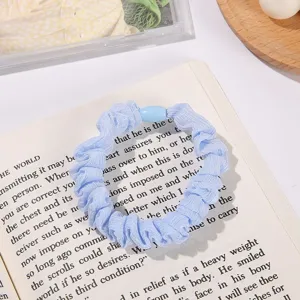 Light blue mesh scrunchie detail shot, showing soft fabric texture and cute bead accessory.