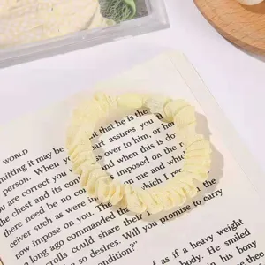 Close-up detail of a soft yellow mesh hair scrunchie, elegantly placed on vintage book text.