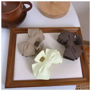 Matte bow hair claw detail featuring three colors for versatile styling and elegant hairstyles.