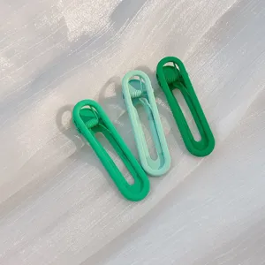 Close up shot of three mint and green geometric duckbill hair clips arranged neatly on fabric.