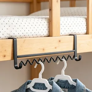 Detail view of the black metal wave hanging hook installed on bunk bed frame for clothes storage.