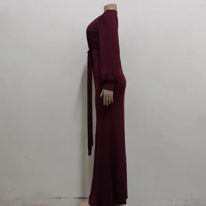 Detail view of a long sleeve maroon maxi dress with side tie belt, tight slim fit style.