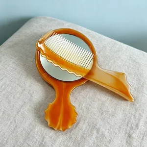 Detailed close-up shot of an amber tortoiseshell pocket comb and handheld makeup mirror set.