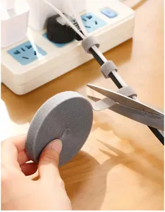 Nahaufnahme einer grauen Nylon-Klettbandrolle, die mit einer Schere zum Ordnen geschnitten wird.