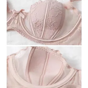 Close-up detail shot of pink lace underwire bra cup, mesh splicing and cute bow decoration.