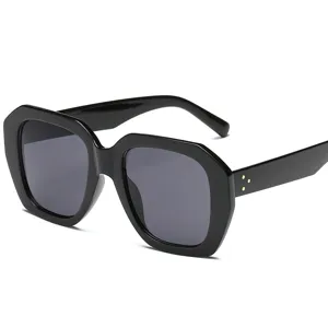 Modische schwarze geometrische Sonnenbrille mit dickem Rahmen und goldenen Akzenten.