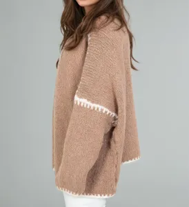 Detail shot of women's oversized chunky knit cardigan sweater in camel with white trim.