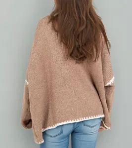 Detail view of a loose brown chunky knit cardigan sweater with white trim, back view.