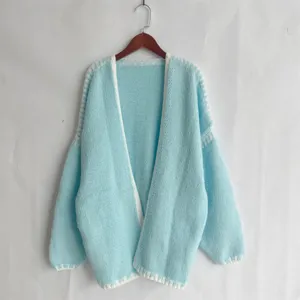 Light blue chunky knit cardigan detail featuring long sleeves, open front and white trim.