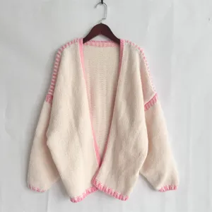 Close up view of the cozy pink and white knit texture, thick yarn cardigan sweater detail.