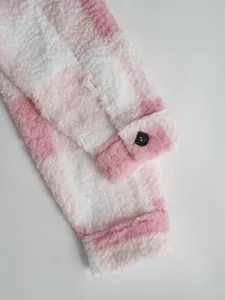 Detailed shot of pink and white plaid fleece jacket sleeve with soft fabric and black button.